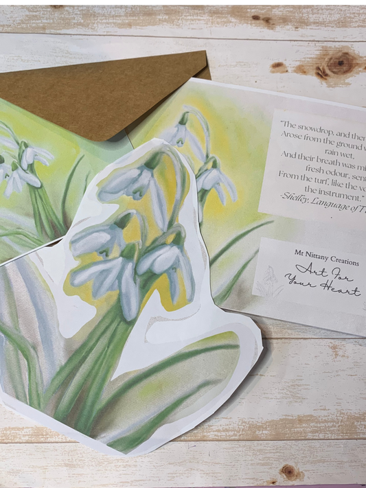 Card with snowdrop illustration and envelope on a wooden surface
